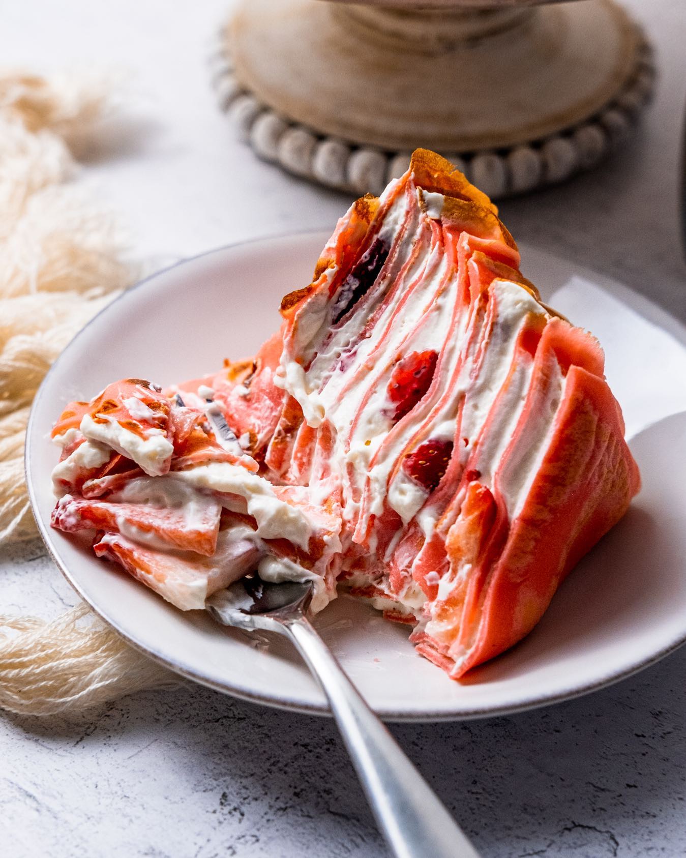 A delicate crepe cake layered with fluffy cream cheese filling and fresh strawberries, perfect for any occasion.